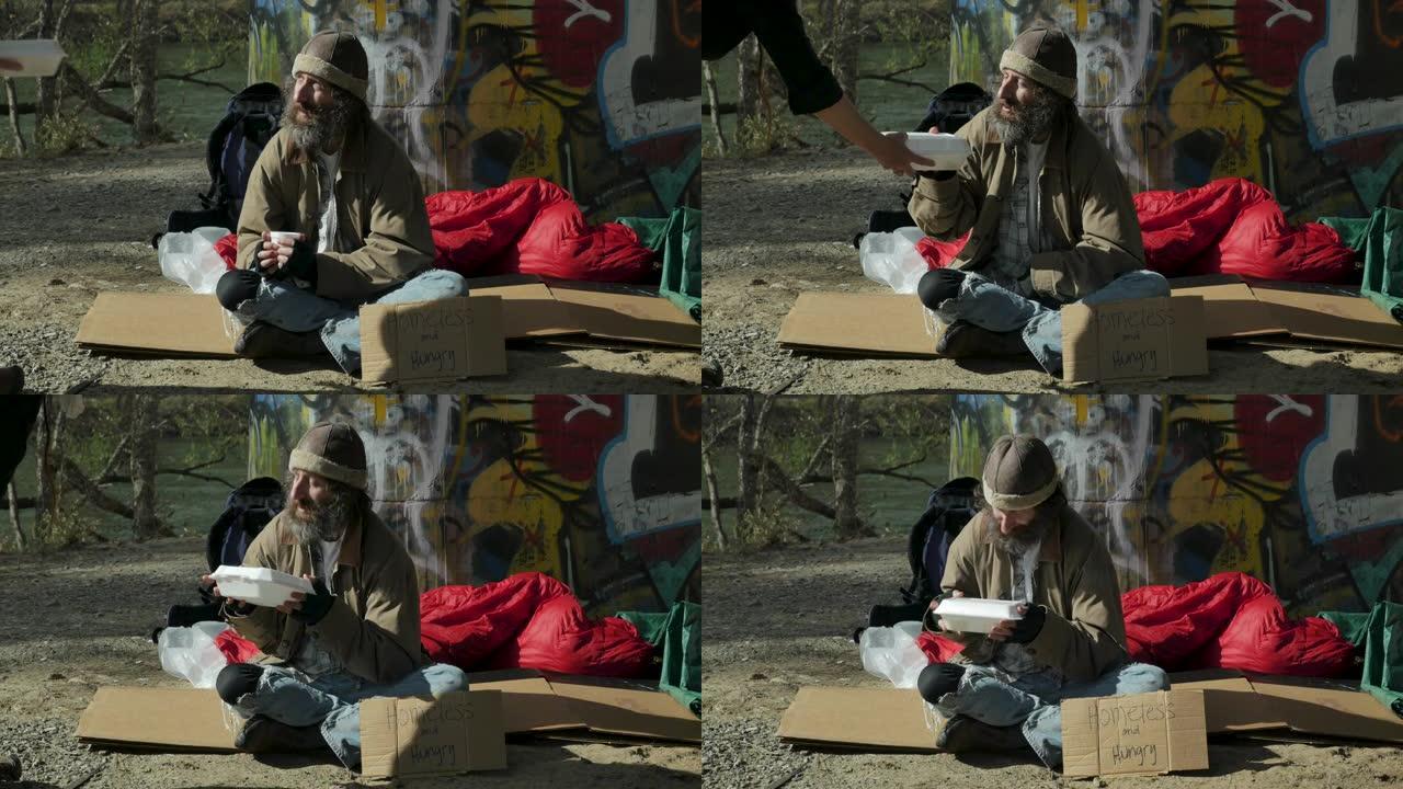 一个女人把一盒可以带走的食物送给一个饥饿的无家可归的人