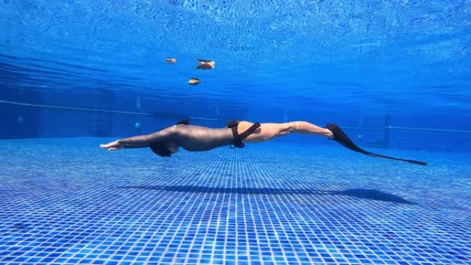水下景观跟踪女人穿一件长袖比基尼剪裁潜水服做动态呼吸暂停游泳鳍海豚踢单鳍