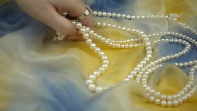 慢动作从时尚的多色柔软织物中取出珍珠首饰。