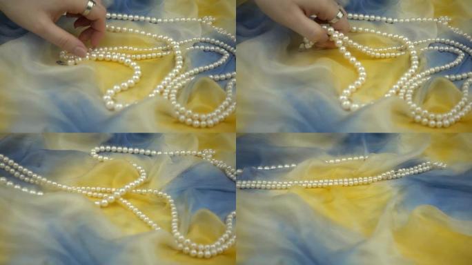 慢动作从时尚的多色柔软织物中取出珍珠首饰。