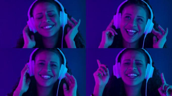 一位年轻可爱的女性非洲裔美国人的肖像看着相机，喜欢用白色大耳机听音乐。用紫色和蓝色霓虹灯照亮的特写脸