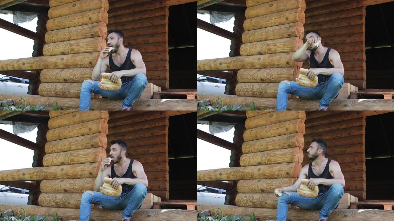 一个英俊的男人蹲在房子的门口，吃开胃的面包。