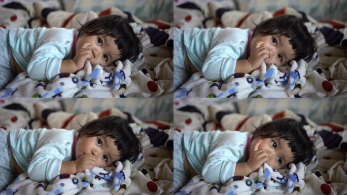 可爱的亚洲婴儿在床上吮吸手指