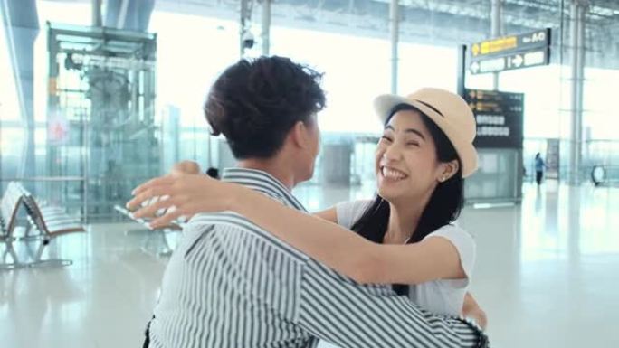 亚洲妇女到达机场并从到达大厅出来，她的丈夫或男友与她见面并拥抱。