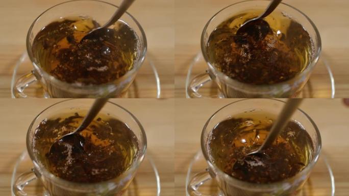 一杯新鲜冲泡的红茶充分搅拌糖，放在木制桌子上，逸出蒸汽，温暖柔和。透明玻璃杯中新鲜酿造的红茶。下午茶