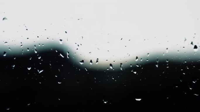 小雨背景，玻璃上的雨，滴在窗户上的水滴，窗外的闪电，雷雨，水倾泻。