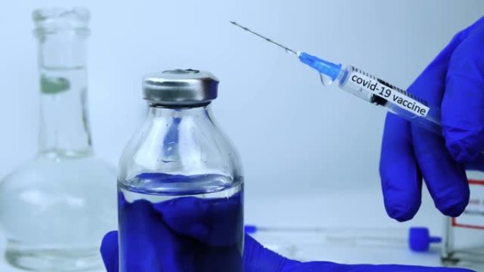 演示一种抗冠状病毒感染的测试疫苗，一名医生拿着一个注射器，手里拿着病毒的药物，新型冠状病毒肺炎感染的