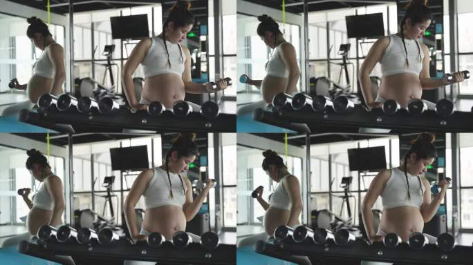 怀孕的妇女在健身房锻炼身体举哑铃撸铁