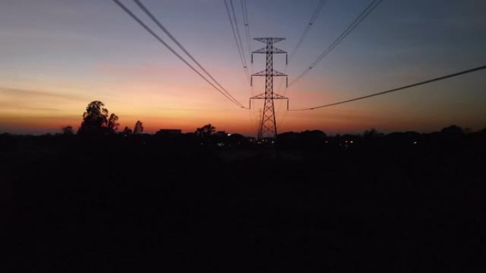 日落黄昏时野外高压电力线电力挂架鸟瞰车