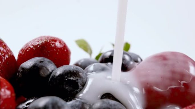 将酸奶或牛奶倒在有机新鲜蓝莓和草莓上。鲜奶油浆果。有机素食概念。特写，4k分辨率。