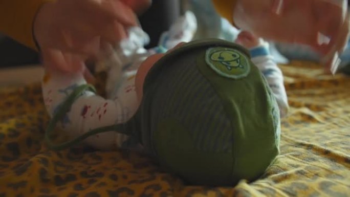 微笑的宝贝躺在床上。母亲给婴儿戴上帽子。特写镜头。