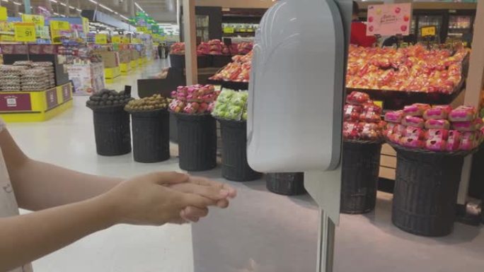 女人的手使用自动消毒机在超市洗手