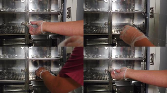 试管婴儿手术的特写镜头。胚胎学家在保护手套将试管和收集的鸡蛋样品放入生物实验室的冰箱。试管婴儿卵泡穿