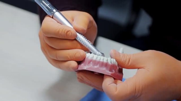 牙科在实践中。牙医在牙颌的印记上练习。新手牙医用打字机在牙齿模型上钻一个洞