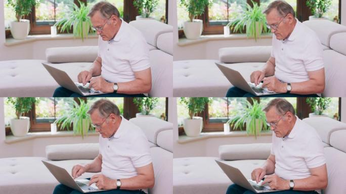 一位退休的老人在家中沙发上的笔记本电脑上打字。年迈的祖父戴着眼镜，在客厅用笔记本电脑工作