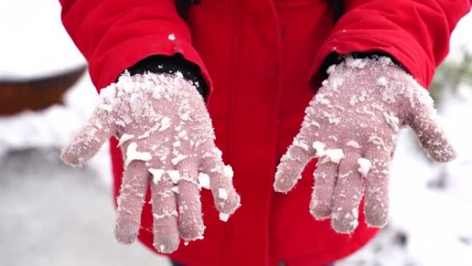 女人的手戴着雪的手套。冬天，无法辨认的女人在街上握着拳头