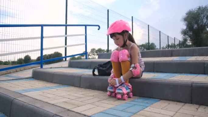 小女孩第一次来到轮滑公园学习轮滑。学龄前的漂亮孩子穿着安全套装，穿上粉色旱冰鞋，4k慢动作50 FP