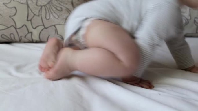腿粗的小男孩婴儿在床上爬行，背景，年龄7个月