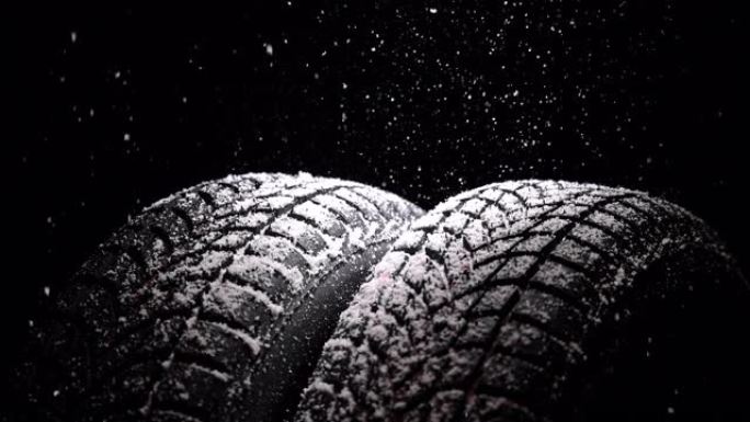 黑色背景上的冬季汽车轮胎和雪雨，4k慢动作视频