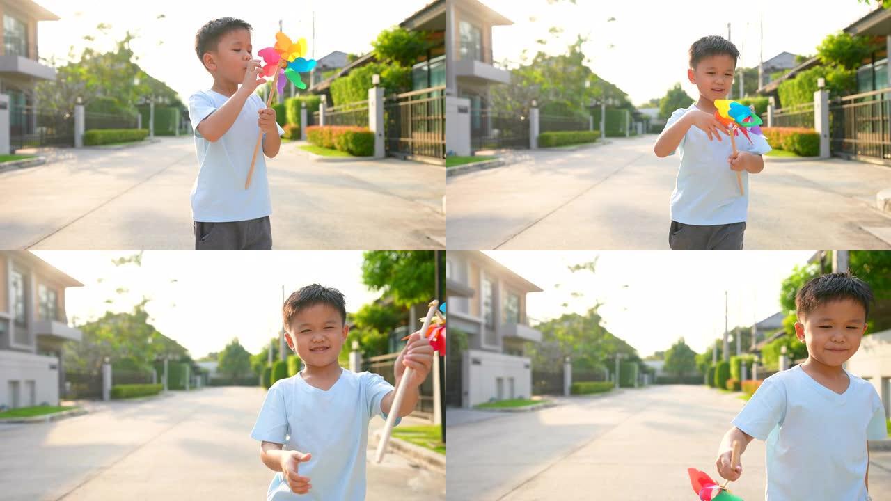 亚洲孩子在住宅区用彩色风车奔跑。纯真和自由的概念