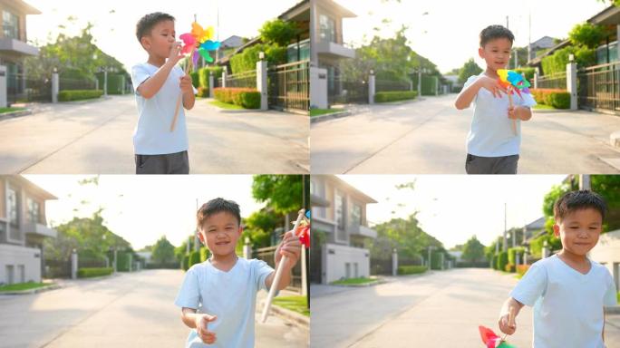 亚洲孩子在住宅区用彩色风车奔跑。纯真和自由的概念