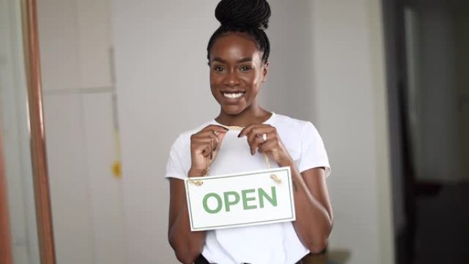 新型冠状病毒肺炎大流行后，美国黑人妇女在一家小商店里举着开放标志