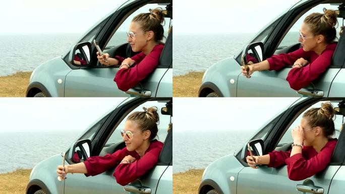 年轻女子在海岸上的一辆汽车上的智能手机上自拍