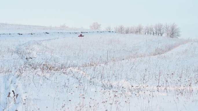 小女孩骑在户外小山上的充气雪橇上