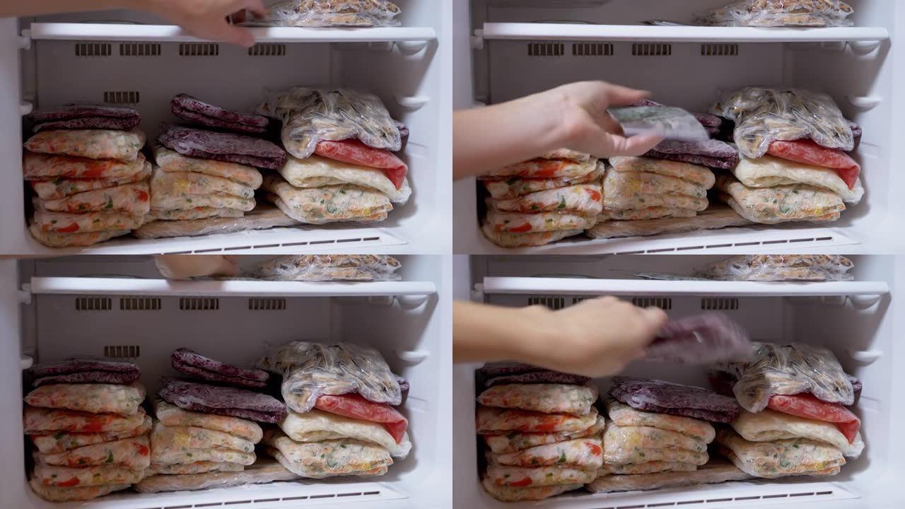 女性的手在冰箱中放置冷冻的蔬菜团块。冷冻蔬菜
