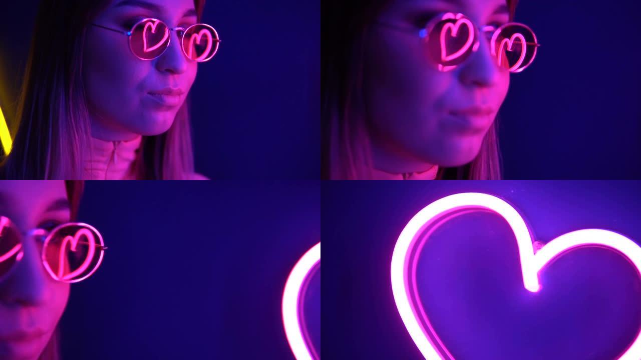 霓虹灯背景上戴着眼镜的时尚女孩。霓虹灯的心在眼镜中反射。