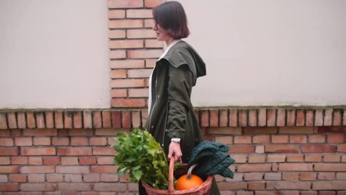 女人手里拿着一篮子蔬菜。在人行道上迈出一步
