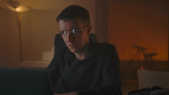 一名男子在笔记本电脑前工作时摘下眼镜，并进行眼部按摩