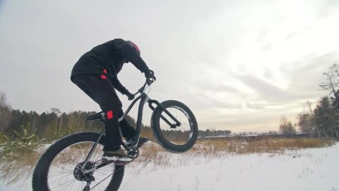 专业极限运动员骑自行车的人在户外骑胖自行车。骑自行车的人在冬季雪林骑行。男子在山地自行车上做试验把戏