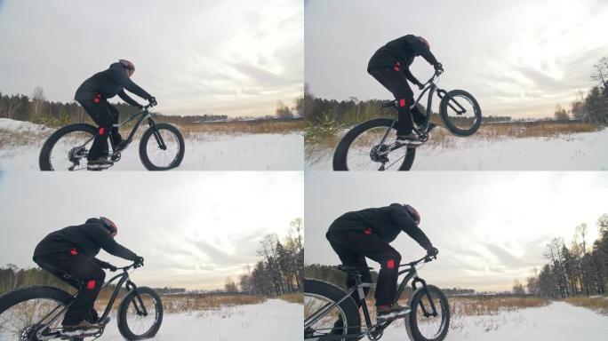 专业极限运动员骑自行车的人在户外骑胖自行车。骑自行车的人在冬季雪林骑行。男子在山地自行车上做试验把戏