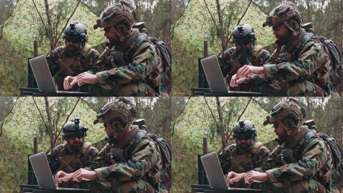 在一个临时森林基地里，身着制服的大胡子士兵坐在军用运输箱上，用笔记本电脑分析数据，制定战术。在背景中