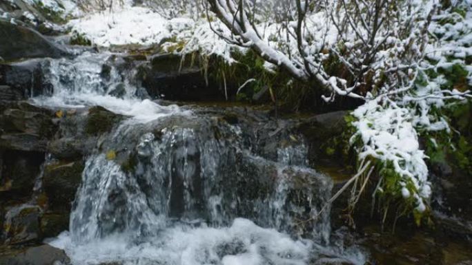 慢动作。在山河上下雪，流淌着石头巨石和石头急流。小溪里快速泼水。冬天的山溪。
