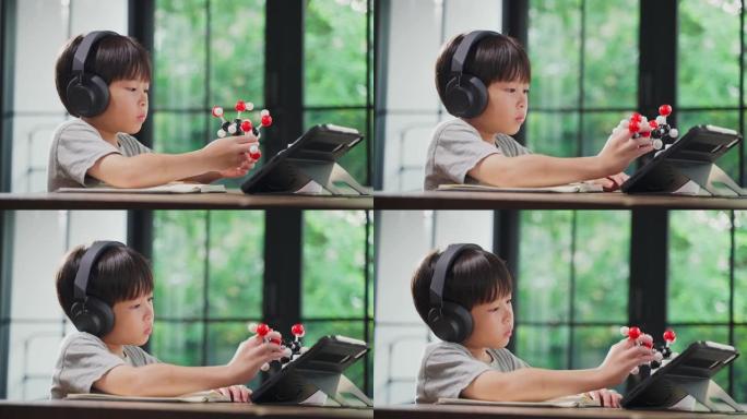 亚洲小男孩通过在家学习和学校老师在线教学来组装分子模型。家庭学校的孩子练习通过远程应用程序与老师思考