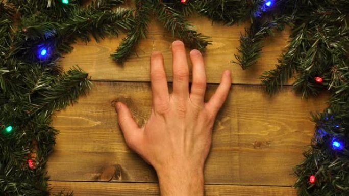 手在带有闪烁花环的装饰木制圣诞桌上轻拍他的手指。