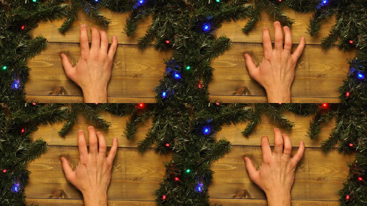 手在带有闪烁花环的装饰木制圣诞桌上轻拍他的手指。