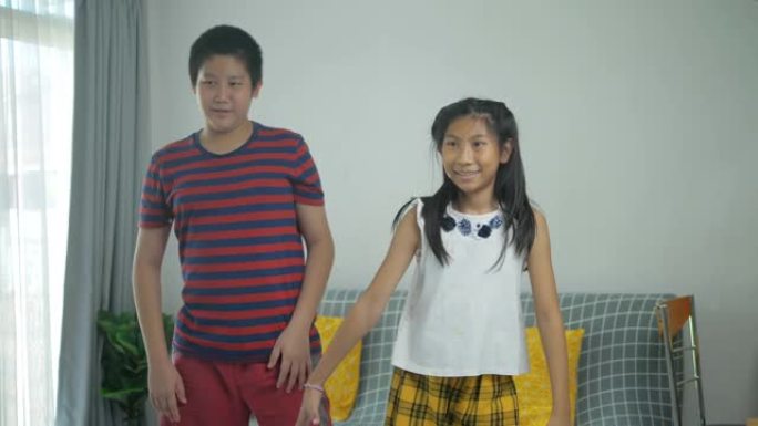 快乐的亚洲青春期男孩和他的妹妹一起在家练习舞蹈，生活方式理念。