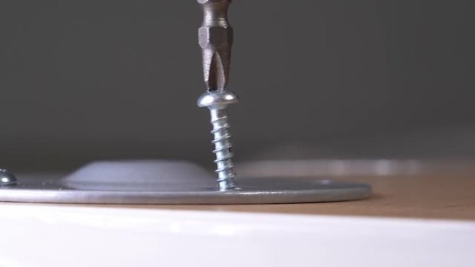 螺丝刀将螺钉拧入桌腿支架。