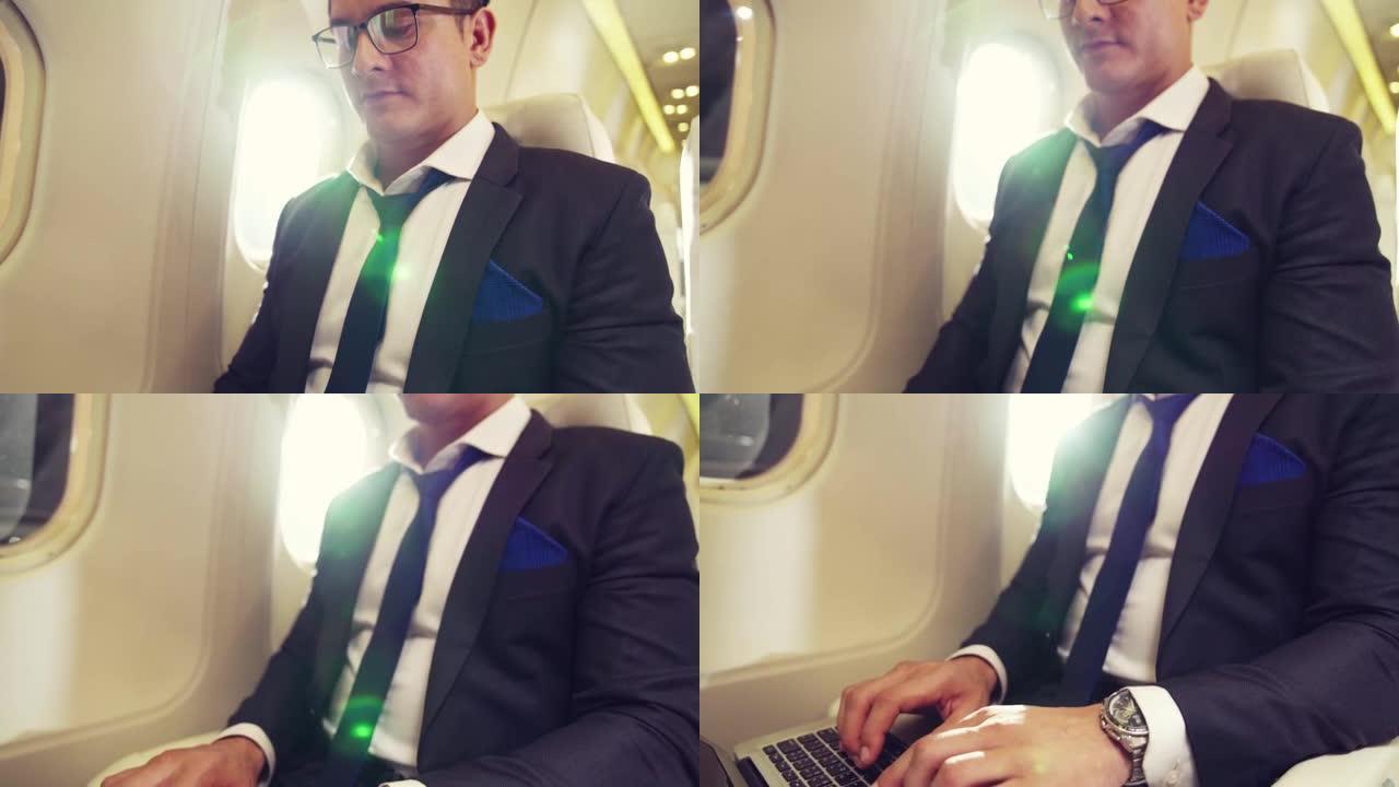 在飞机上使用笔记本电脑的年轻商人