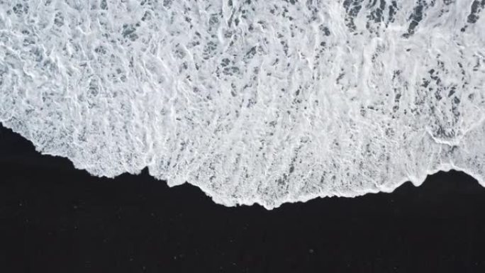 黑色沙滩上白色冲浪的银色小径