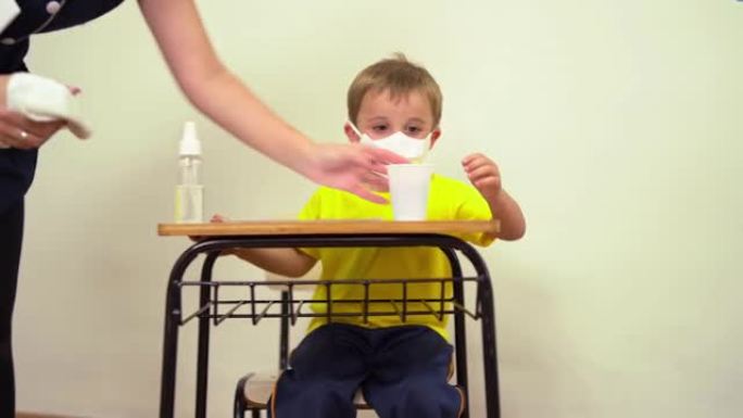 老师给小男孩消毒学校用品。