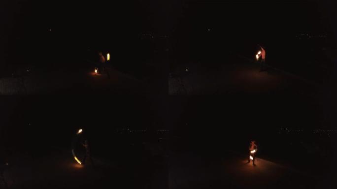 年轻的金发男性用火耍花招，晚上在黑城背景上旋转两个燃烧的火炬。旅行