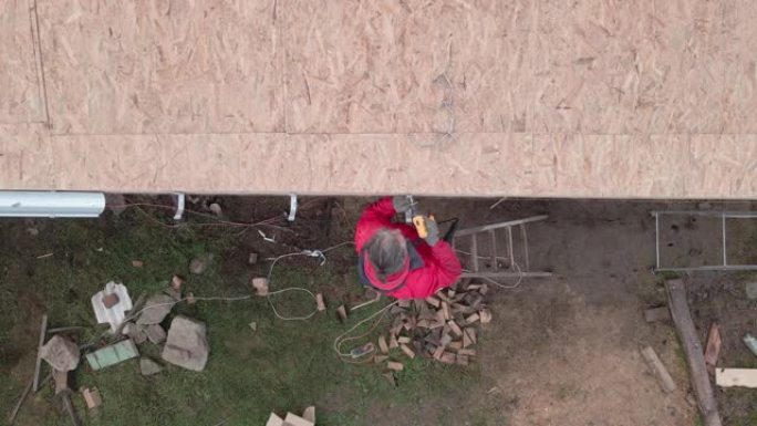 DIY。家庭装修。一个修理谷仓屋顶的人的鸟瞰图。活跃的高级男子在新型冠状病毒肺炎大流行期间呆在家里的
