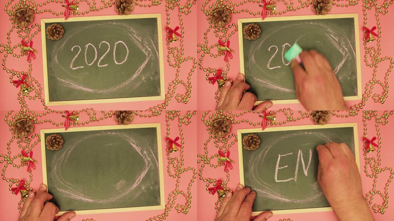 一个男人的手抹去了一块黑板上的2020，并写下了结尾。