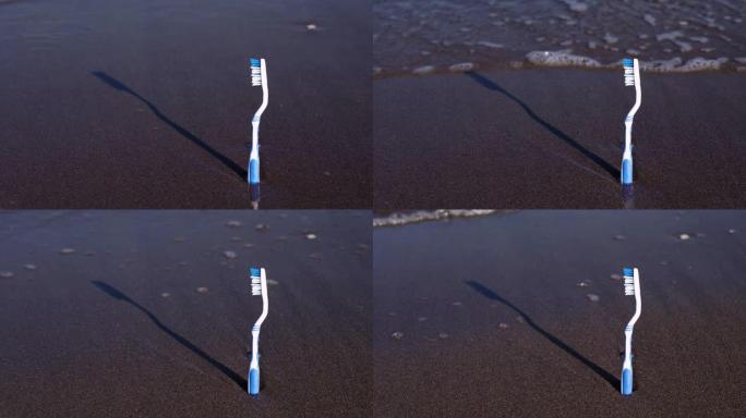 塑料牙刷站在湿沙和海浪卷中