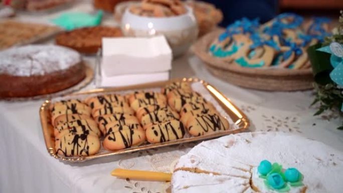 自助餐桌上有各种不同的烘焙蛋糕和饼干，美味的甜饼撒上糖粉，装饰着蓝色的糖花。派对庆典甜点宴会