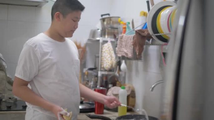 亚洲青春期男孩在家厨房洗碗，生活方式概念。